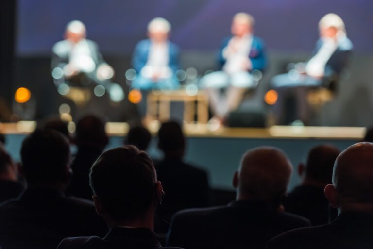 The head of the listener with the receiver in the ear, in the background the silhouettes of people conducting the conference